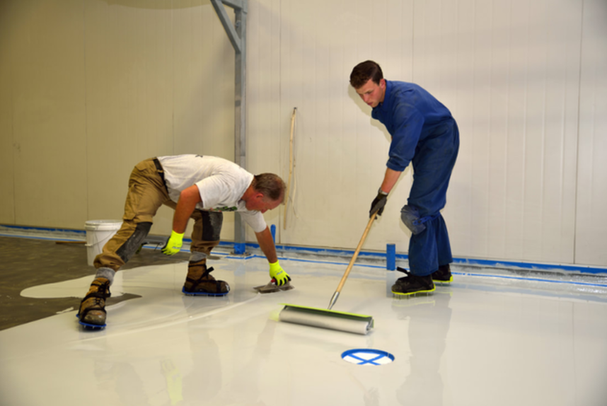 Deux employés de Plancher Epoxy Granby applique l'epoxy sur le plancher à l'aide d'une truelle et d'un rouleau.